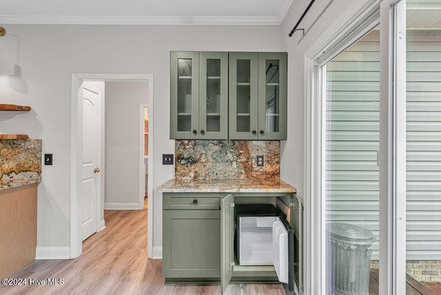 kitchen with light stone countertops, ornamental molding, light hardwood / wood-style flooring, and green cabinets