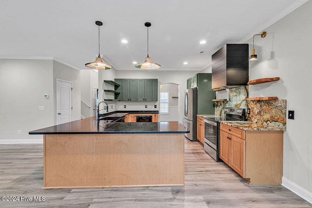 kitchen featuring stainless steel appliances, wall chimney range hood, sink, green cabinetry, and hanging light fixtures