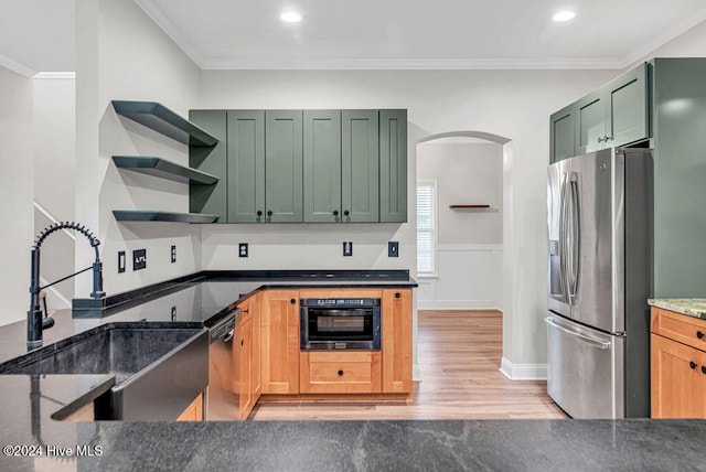 kitchen with sink, crown molding, green cabinetry, light hardwood / wood-style flooring, and appliances with stainless steel finishes