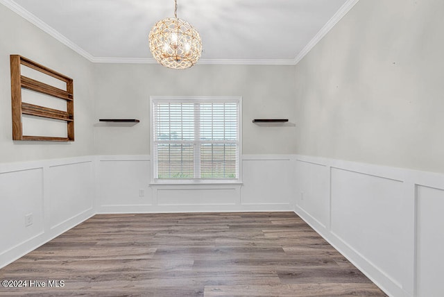 spare room with light hardwood / wood-style floors, ornamental molding, and an inviting chandelier