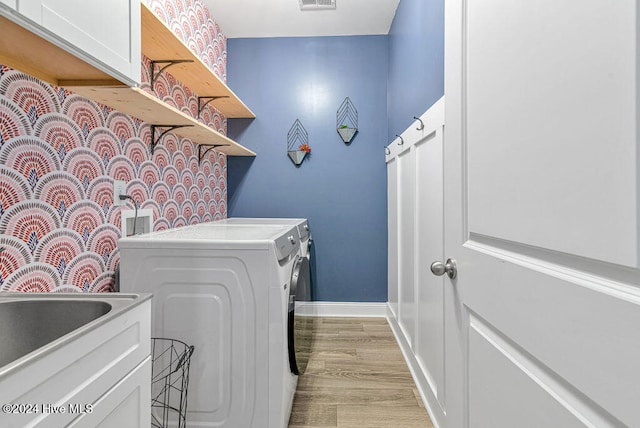 laundry room with cabinets, light wood-type flooring, separate washer and dryer, and sink