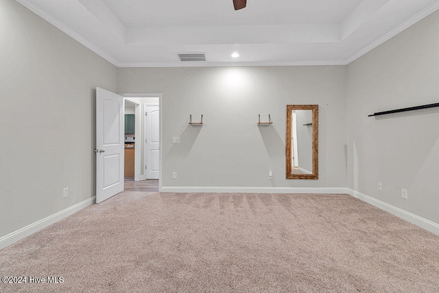 carpeted empty room with ceiling fan, a raised ceiling, and crown molding