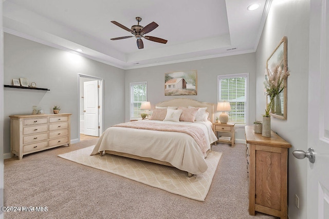 bedroom with ceiling fan, a raised ceiling, ensuite bathroom, light carpet, and ornamental molding