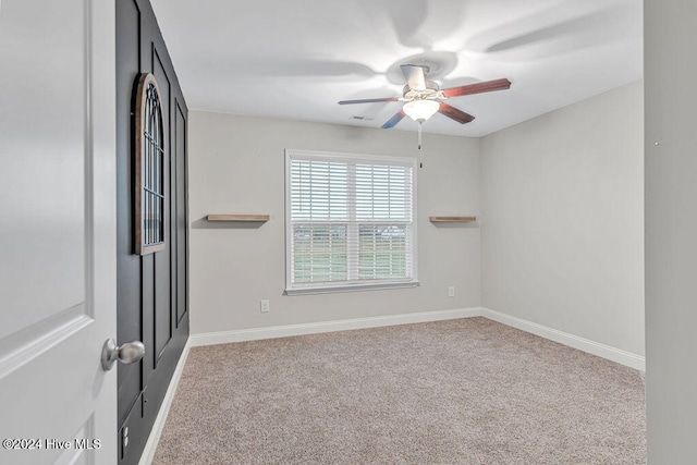 spare room featuring light colored carpet and ceiling fan