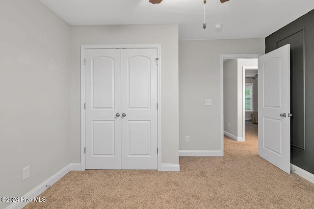 unfurnished bedroom with ceiling fan, light colored carpet, and a closet