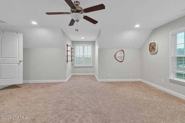 empty room featuring ceiling fan, plenty of natural light, light colored carpet, and vaulted ceiling