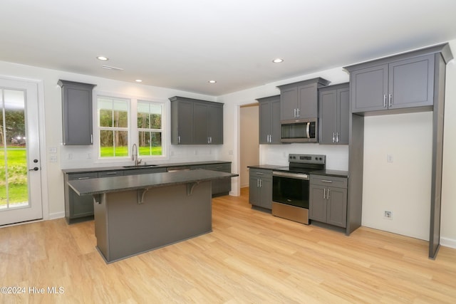 kitchen with sink, appliances with stainless steel finishes, gray cabinetry, and a kitchen island