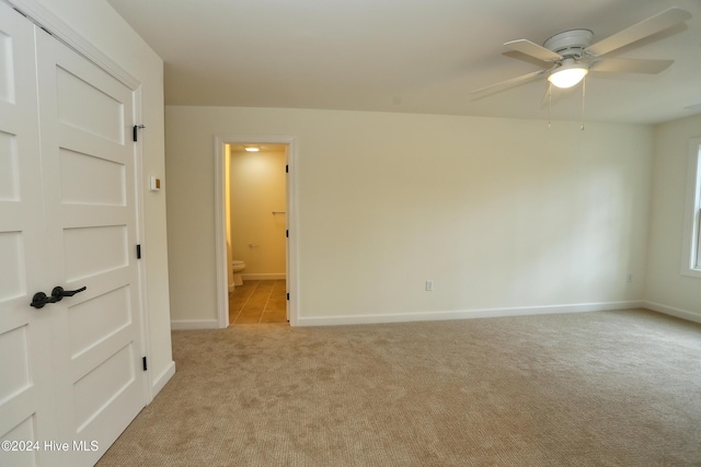 spare room with ceiling fan and light colored carpet