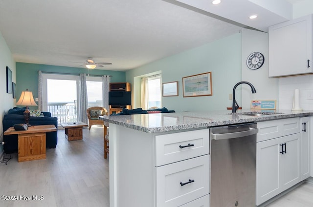 kitchen featuring light stone counters, stainless steel dishwasher, sink, white cabinets, and light hardwood / wood-style floors