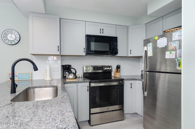 kitchen featuring light stone countertops, appliances with stainless steel finishes, tasteful backsplash, and sink