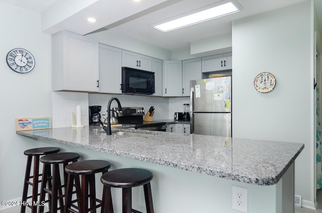 kitchen with kitchen peninsula, decorative backsplash, sink, and black appliances