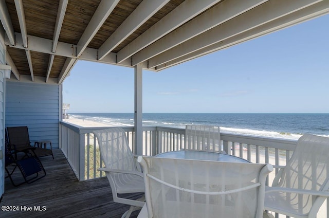 wooden terrace featuring a view of the beach and a water view