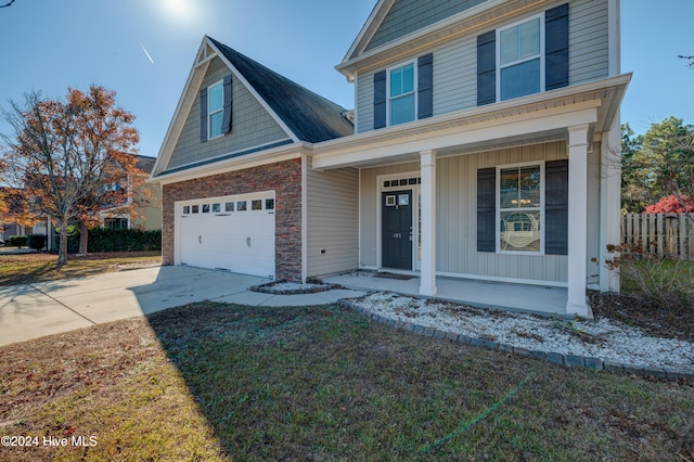 front facade featuring a porch, a garage, and a front lawn