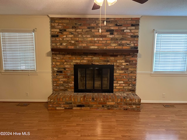 room details featuring ornamental molding, a textured ceiling, ceiling fan, wood-type flooring, and a fireplace