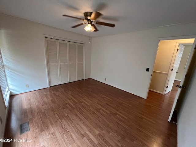 unfurnished bedroom featuring ceiling fan, a closet, and dark wood-type flooring