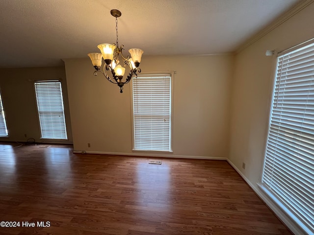 spare room featuring dark hardwood / wood-style flooring, ornamental molding, and an inviting chandelier