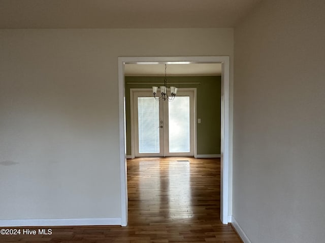 corridor with hardwood / wood-style floors and french doors