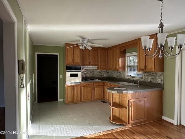 kitchen with dark countertops, oven, under cabinet range hood, electric stovetop, and a sink