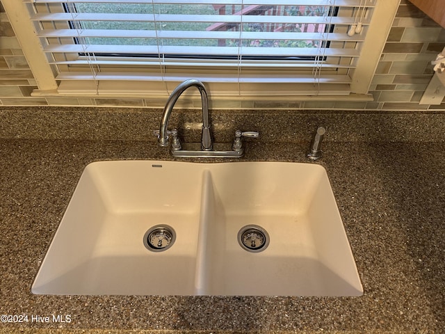 interior details featuring dark stone countertops, sink, and backsplash