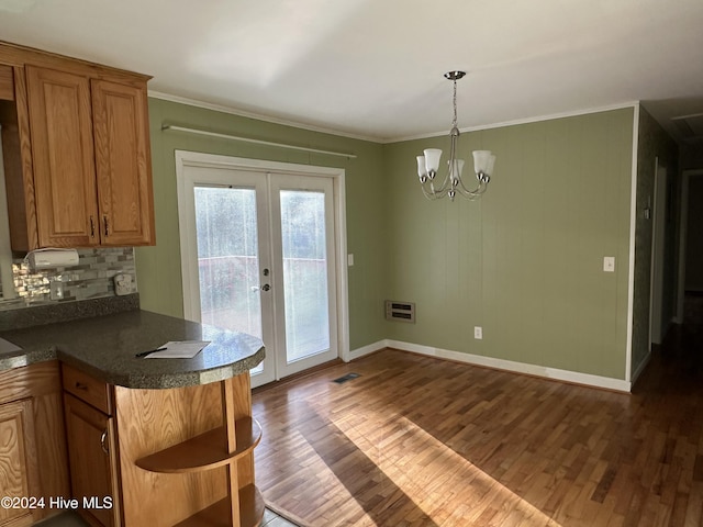 kitchen with dark wood-type flooring, french doors, tasteful backsplash, crown molding, and an inviting chandelier