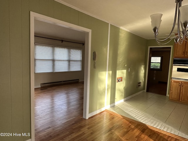 interior space featuring visible vents, baseboards, wood finished floors, baseboard heating, and crown molding