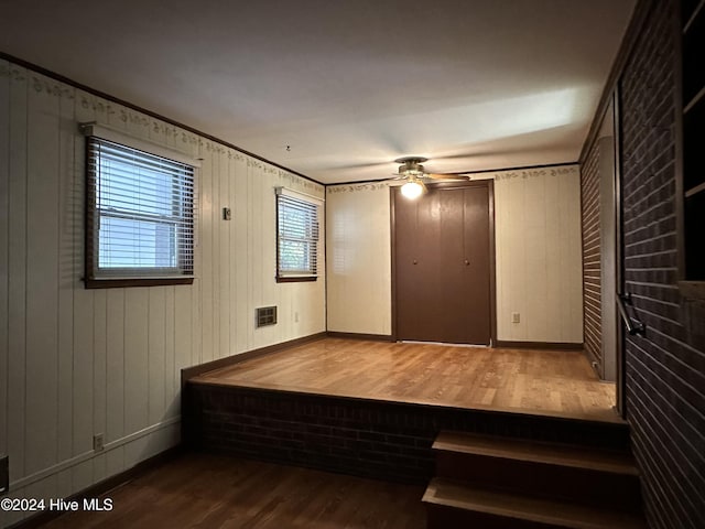 interior space with hardwood / wood-style flooring, ornamental molding, and wood walls