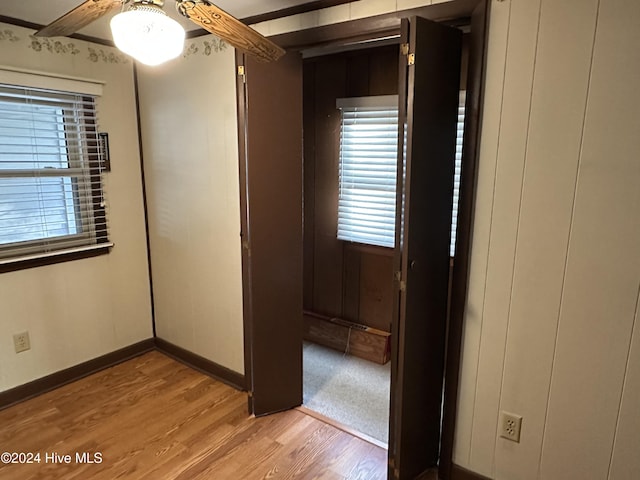 unfurnished bedroom with light wood-type flooring, multiple windows, ceiling fan, and baseboards