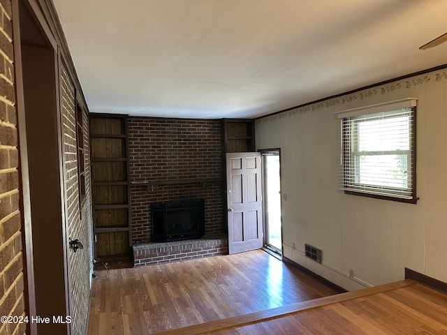 unfurnished living room featuring dark wood-type flooring, a brick fireplace, and visible vents