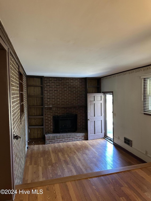 unfurnished living room with plenty of natural light, a fireplace, hardwood / wood-style floors, and built in features