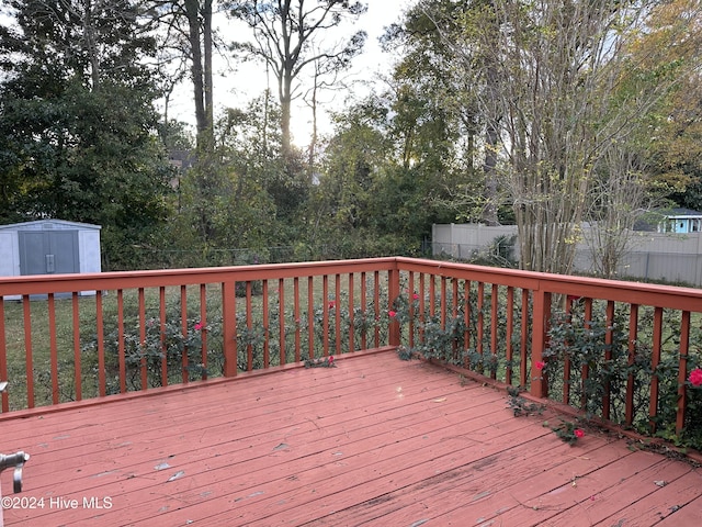 wooden terrace featuring an outbuilding, a shed, and fence