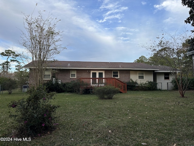 view of front of house with brick siding, a deck, and a front yard