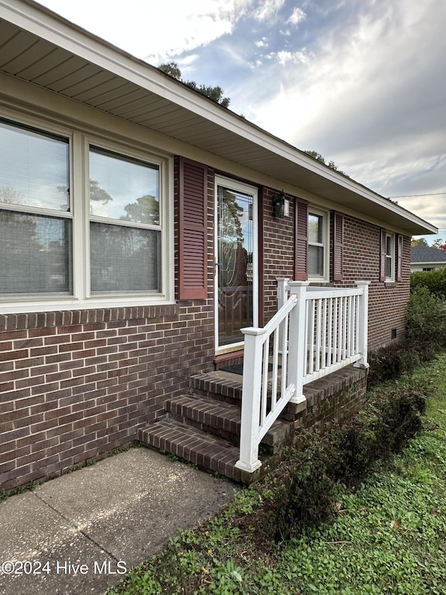 view of exterior entry featuring crawl space and brick siding