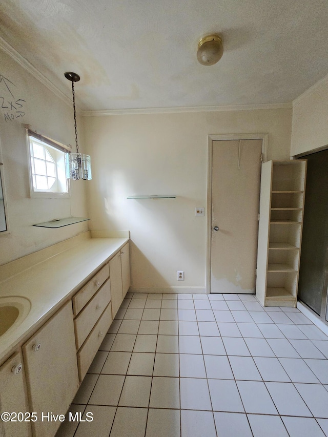 kitchen with hanging light fixtures, light tile patterned floors, light countertops, and crown molding