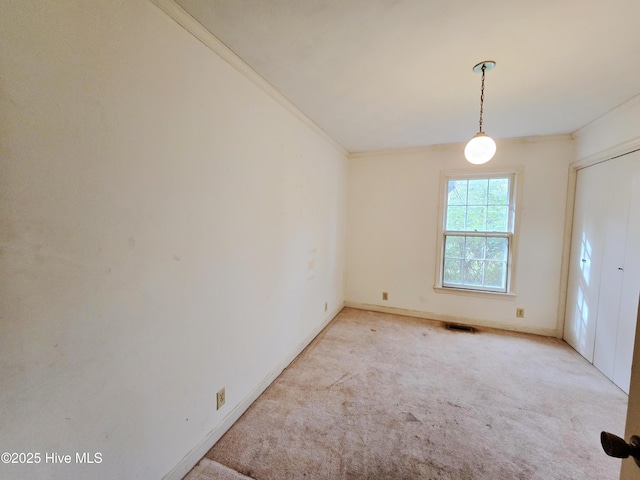 spare room featuring ornamental molding, light carpet, visible vents, and baseboards