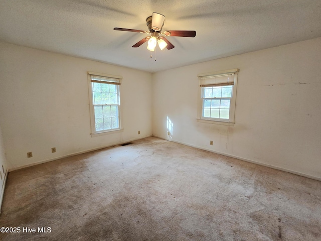 carpeted spare room with baseboards, visible vents, a ceiling fan, and a textured ceiling