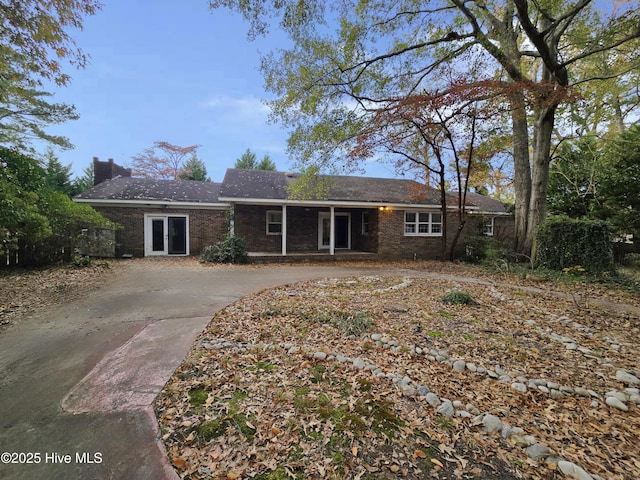 ranch-style home with concrete driveway, brick siding, and a chimney