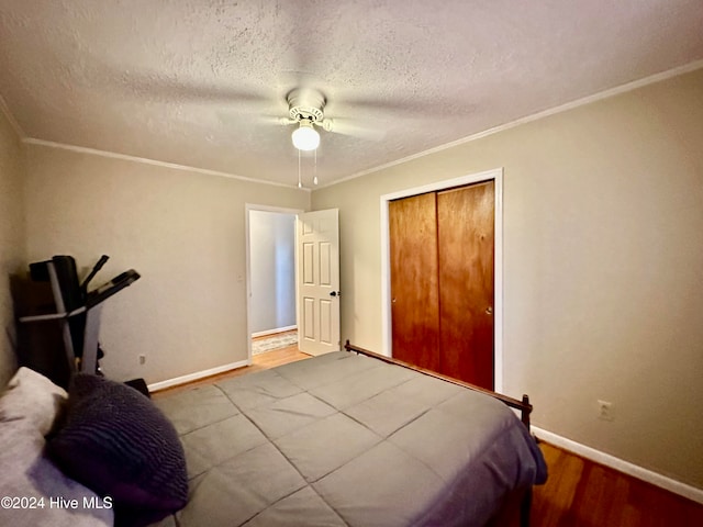 bedroom with ceiling fan, crown molding, light hardwood / wood-style floors, a textured ceiling, and a closet