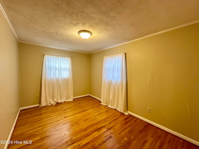 spare room with hardwood / wood-style floors, a textured ceiling, and ornamental molding