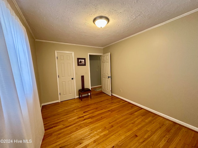 unfurnished room featuring hardwood / wood-style floors, a textured ceiling, and ornamental molding