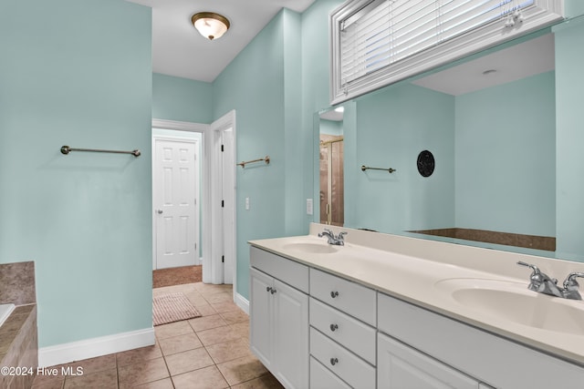 bathroom with tile patterned flooring, vanity, and tiled tub