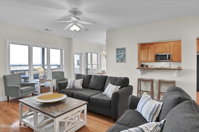 living room featuring ceiling fan with notable chandelier and light hardwood / wood-style floors