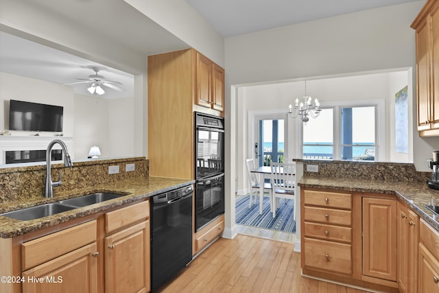 kitchen featuring sink, light hardwood / wood-style flooring, dark stone countertops, a water view, and black appliances