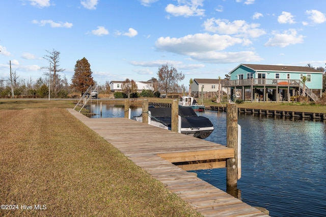 view of dock with a lawn and a water view