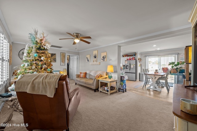 living room featuring light carpet, ceiling fan, and crown molding