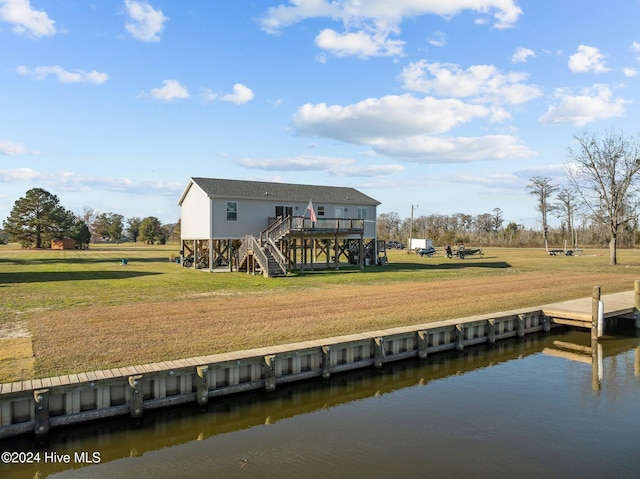 rear view of property featuring a deck with water view and a yard