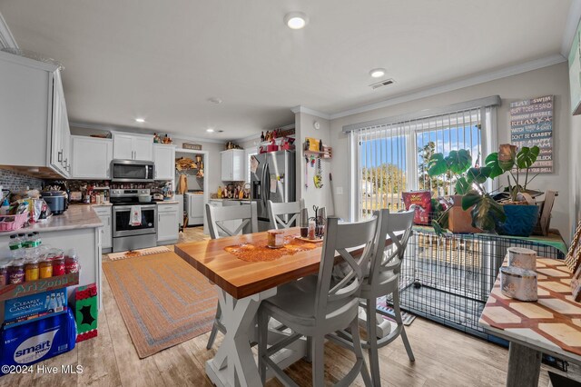 dining space featuring crown molding, light hardwood / wood-style flooring, and washer / dryer