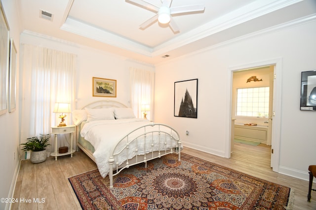 bedroom with a raised ceiling, ceiling fan, crown molding, hardwood / wood-style floors, and connected bathroom