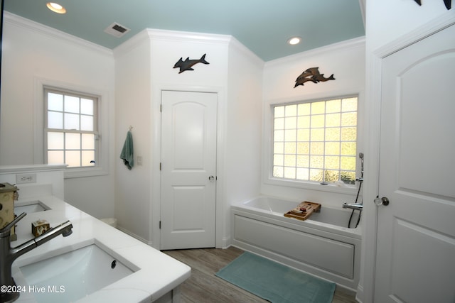 bathroom with a tub to relax in, crown molding, vanity, and hardwood / wood-style flooring