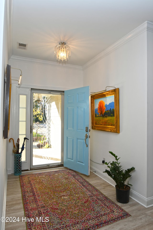 entrance foyer featuring hardwood / wood-style floors, crown molding, and a notable chandelier