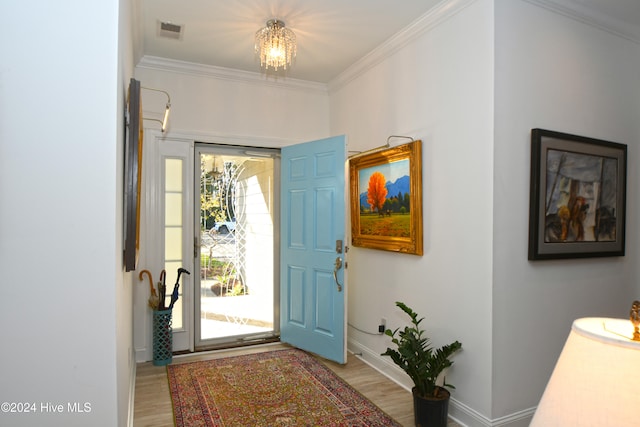 foyer featuring hardwood / wood-style flooring, an inviting chandelier, and ornamental molding